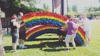 volunteers work together to install a large crepe-paper covered rainbow at Ogden Pride